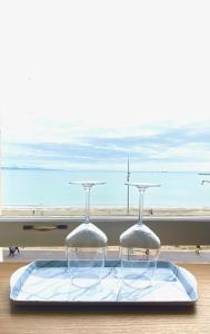 two wine glasses on a tray with a view of the beach at The Angove in Weymouth