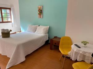a bedroom with a bed and a table and a yellow chair at Pousada Jardim do Éden in Serra do Cipo +11 photos