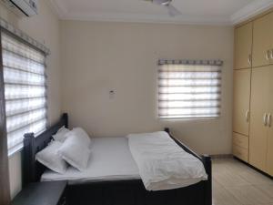 een slaapkamer met een bed met witte lakens en kussens bij Lakeside Lodge in Apenkwa
