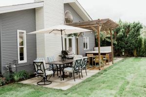 a patio with a table and chairs and an umbrella at Charming Kelowna Haven with Hot Tub, Parking, Pet-Friendly Bliss in Kelowna