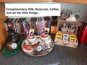 a table topped with cups and bowls of coffee and books at F1 MAISON 108 - Holiday Home - Full Kitchen - Street FREE PARKING, NETFLIX - 68Mbps BT WIFI - DVD's - Welcome Tray - By Corner from Gavin n Stacey Film House in Barry