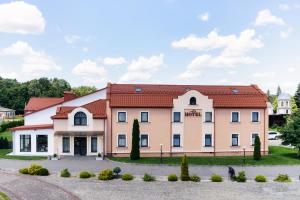 een groot roze gebouw met een rood dak bij Підгорецький маєток - готель in Pidhirtsi