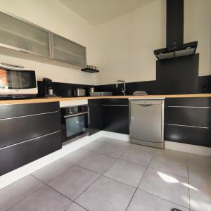 a kitchen with black and white counters and appliances at Le Céles'Thym - SPA Privatif in Conques-sur-Orbiel