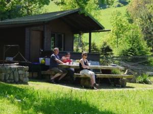 un grupo de personas sentadas en una mesa de picnic frente a una cabaña en Ferienwohnungen Maierhof Oberried, en Oberried