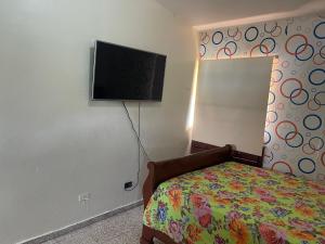 Schlafzimmer mit einem Bett und einem Flachbild-TV in der Unterkunft Residencial Parque del Este, Clásico Victoriano, 4-A in Los Tres Ojos de Agua