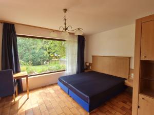 ein Schlafzimmer mit einem blauen Bett und einem großen Fenster in der Unterkunft Alpenblick Pang in Rosenheim