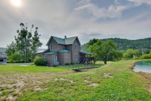 una casa en un campo junto a un cuerpo de agua en The Olde Homestead with Fire Pit and Mountain Views!, en Coudersport