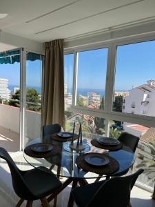 a dining room with a glass table and chairs and windows at Luxury Bonanza in Benalmádena