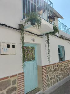 een huis met een blauwe deur en een balkon bij La casa de tío Vidal in Pedro Bernardo