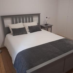 a bedroom with a large white bed with two pillows at Moinho das Cavadas in Ponte da Barca