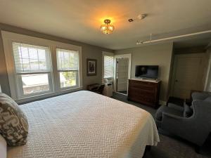 a bedroom with a bed and a tv and windows at Gifford House in Provincetown