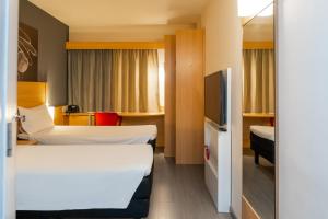 a hotel room with two beds and a tv at Ibis Porto Alegre Assis Brasil - Estacionamento Gratuito para hospedes in Porto Alegre +25 photos