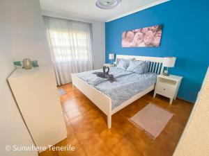 Un dormitorio con una cama y una pared azul. en Spacious apartment with private garden in Tenerife south, en San Miguel de Abona