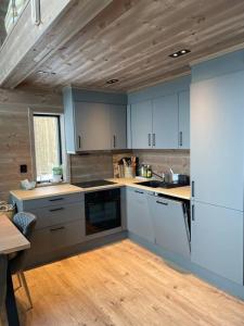 a kitchen with white cabinets and a wooden ceiling at Rindabotn Fjelltun in Sogndal