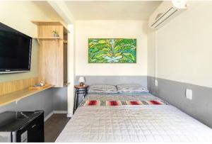 a bedroom with a bed with a tv on the wall at Guest room Casa SEA in Florianópolis