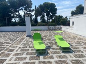 two green lounge chairs and tables on a patio at La dimora nonna Eugy in Polignano a Mare