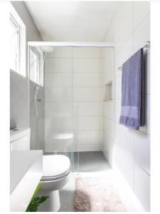 um banheiro branco com vaso sanitário e chuveiro em Guest room Casa SEA em Florianópolis mais 22 fotografias