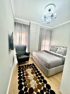 een slaapkamer met een bed, een stoel en een kroonluchter bij Klidi Apartment in Tirana
