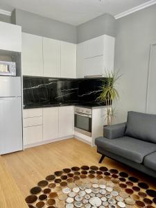 a kitchen with white cabinets and a couch and a rug at Klidi Apartment in Tirana