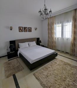 um quarto com uma cama grande e um lustre em Luxury house directly on the beach em Bizerte