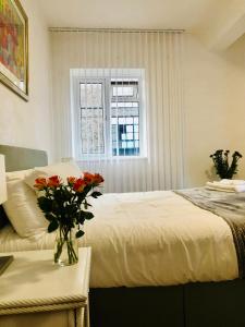 ロンドンにあるCity location- 2 bedroom apartmentのベッドルーム1室(花瓶のあるテーブル付)