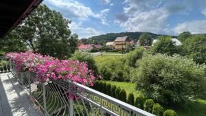 a balcony with pink flowers on a fence at Pokoje u Lusi in Tylicz