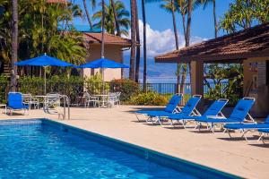 a pool with chairs and umbrellas next to a resort at Makena Surf- CoralTree Residence Collection in Wailea