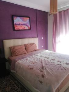 a bedroom with a large bed with a purple wall at شقة مفروشة in Agadir