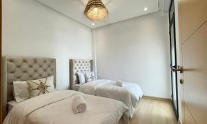 a bedroom with two beds with white sheets at Cosy Bay appartement 4 - 5px in Agadir