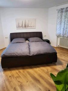 uma cama grande num quarto com piso em madeira em Ferienwohnung am Bodensee em Tettnang