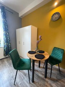 ein Esszimmer mit einem Tisch und 2 grünen Stühlen in der Unterkunft Apartament Kościuszko in Kattowitz