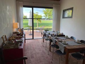 a room with a long table with chairs and a large window at Corte LOIOL in Scorzarolo