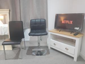 a room with two chairs and a tv and a bed at Family Lodge, Princess Lodge, Executive Lodge, Master's Lodge in Seven Kings