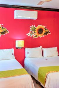 two beds in a room with a red wall at Hotel Gran Centenario in Mérida