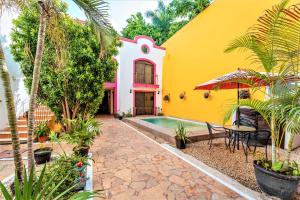 een geel en roze huis met een tafel en stoelen bij Hotel Gran Centenario in Mérida