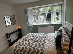 um quarto com uma cama e duas janelas em Lovely 3-Bed House near Birmingham Airport & Nec em Solihull