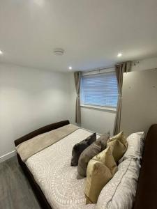 een slaapkamer met een groot bed met kussens en een raam bij Stylish & Cosy 1 Bed Apartment in Swindon