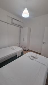 um quarto branco com 2 camas e uma luz em Vivienne's Apartment em Saranda