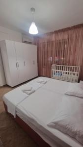 um quarto com uma grande cama branca e armários brancos em Vivienne's Apartment em Saranda