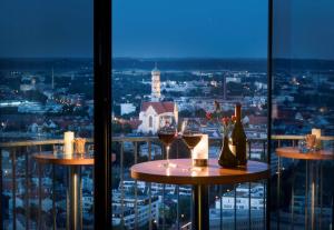 a table with two glasses of wine and a view at Dorint An der Kongresshalle Augsburg in Augsburg