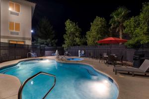 ein Pool in der Nacht mit einem Tisch und einem Sonnenschirm in der Unterkunft Comfort Inn & Suites Las Vegas - Nellis in Las Vegas