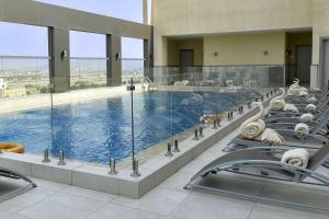 a large swimming pool with lounge chairs in a building at Clarion Hotel Jeddah Airport in Jeddah