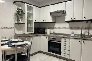 uma cozinha com armários brancos, uma mesa e um lavatório em SanMar em Finisterre