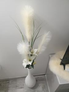 a white vase with white feathers and white flowers at La green in Brétigny-sur-Orge