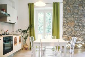 Una mesa blanca y sillas en una cocina con pared de piedra. en Casa Desdy, en Tuscania