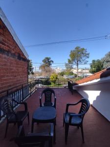 科隆Depto Luis的阳台设有四把椅子和一张桌子,阳台上设有砖砌建筑