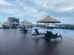 a deck with chairs and umbrellas next to a body of water at Galeno Pollux Habibie in Batam Center