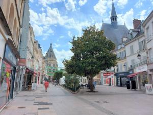 una persona che cammina per una strada di città con edifici di LE CHIC ETHNIC DREUX 52m2 - 50 MIN DE PARIS - PARKING GRATUIT a Dreux