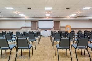 una sala de conferencias con sillas y una pantalla de proyección en Coast Swift Current Hotel, en Swift Current