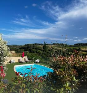 una piscina en un patio con sillas y árboles en Hôtel Restaurant La Bergerie en Aragon